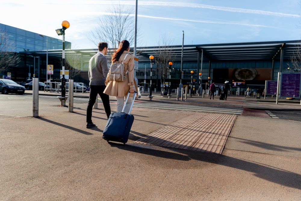Traveler with suitcase walking toward airport shuttle with car park signage visible